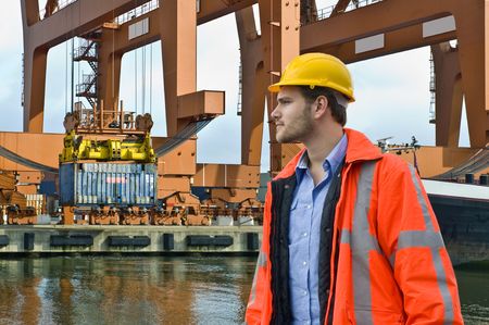 An engineer, closely watching the unloading of a constainer ship in a harbor environment