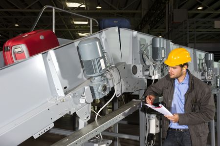 A maintenance engineer inspecting a luggage handling conveyor beltの写真素材