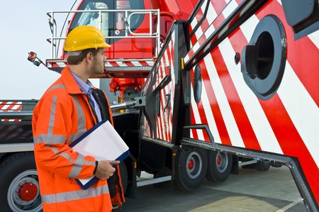 A man, wearing safety gear, inspecting the worlds biggest mobile craneの写真素材