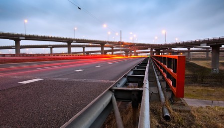 A highway overpass with busy traffic at night. Various roads intertwining with each other