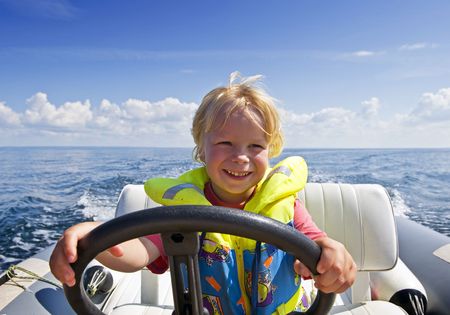 Young boy behind the steering wheel of an inflatable speedboatの写真素材
