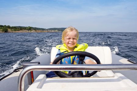 Young boy behind the steering wheel of an inflatable speedboatの写真素材