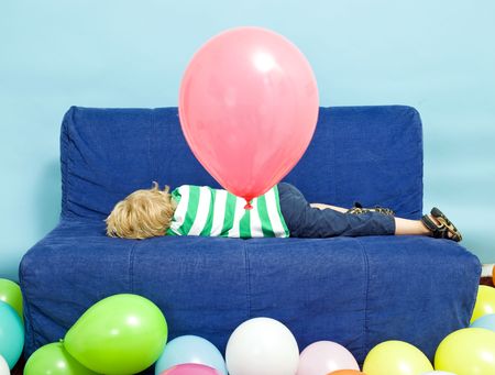 Young Boy lying down on a couch on his birthdayの写真素材