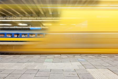 Train departing from a platform, leaving a blur and a glimpse on a waiting train on another platform の写真素材