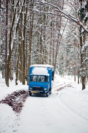 An old soviet truck driving on a snowy road through a forest in the Czech republicの写真素材