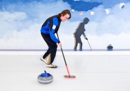 Curling player influencing the curvature of a stone being delivered with his broomの写真素材