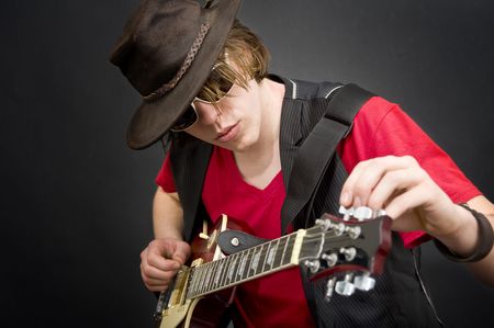 A cool looking guitar player tuning his instrument