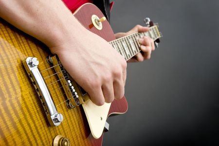 A man's hand striking the strings of a guitar