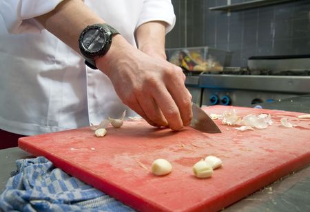 A chef cutting garlic in a professional kitchenの写真素材