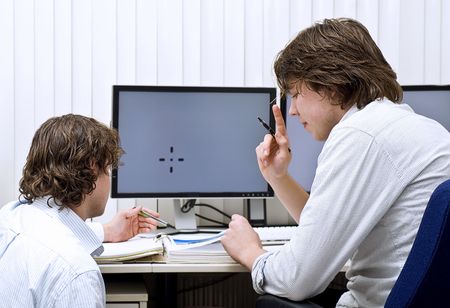 Two co-workers disscussing a thick dossier, one rasing his finger in understanding.の写真素材