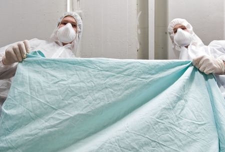 Two forensic investigators covering a dead victim with a sheet, seen from the dead persons...