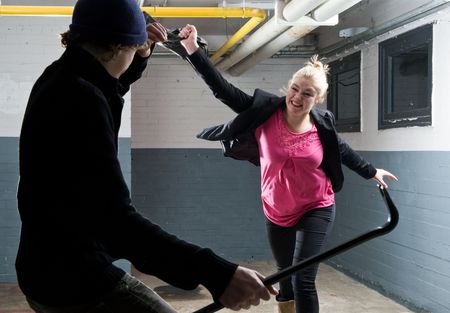 Young woman defending herself with her purse  against a criminal armed with a crowbar.の写真素材