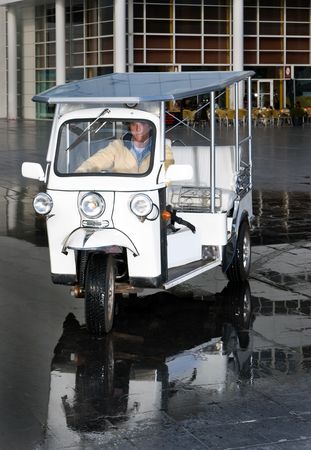 Solar powered electrical tuc tuc approaching the camera in an urban environment