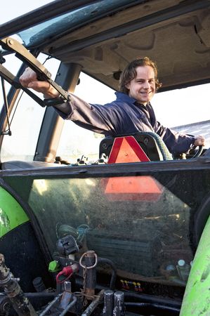 Farm hand looking out the rear window of a tractor, hodling the lever