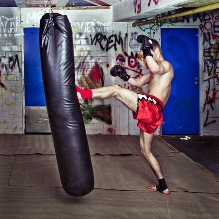 Muay Thai fighter giving a forceful forward kick during a practise round with a boxing bagの写真素材