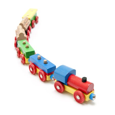 Wooden toy train with a locomotive and five carriages with a subtle reflection on a white background and a shallow depth of fieldの写真素材