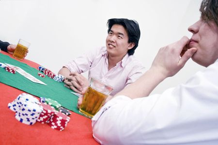 An Asian man sittingat the poker table during a game, ambiguously smiling at the competitionの写真素材
