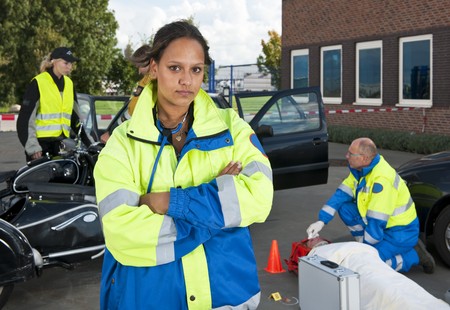 Young female paramedic posing confidently in front of a car accident siteの写真素材