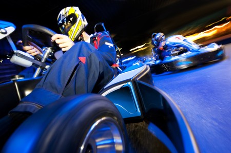 Two go-cart drivers battling in a competitive race on an indoor circuitの写真素材