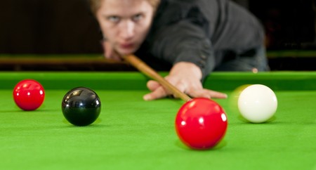 Snooker player placing the cue ball for a shot on black, whilst hitting the red ball (Selective focus and motion blur)の写真素材