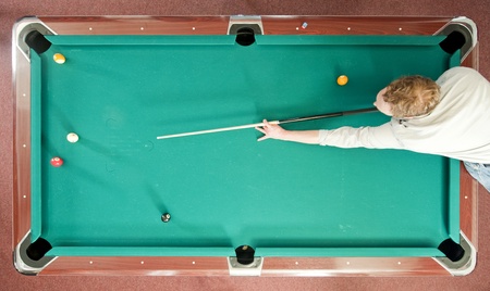 Pool player reaching for a shot, seen from aboveの写真素材