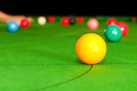 Yellow snooker ball on the table, with the game playing in the background. Selective focus-の写真素材