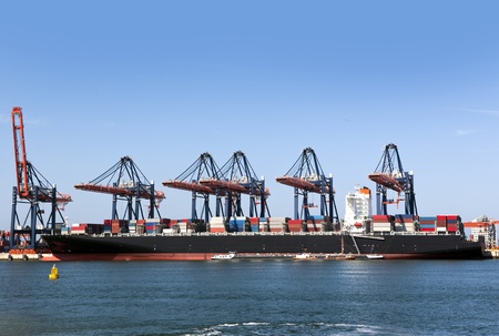 Container ship being unloaded at an industrial harbor