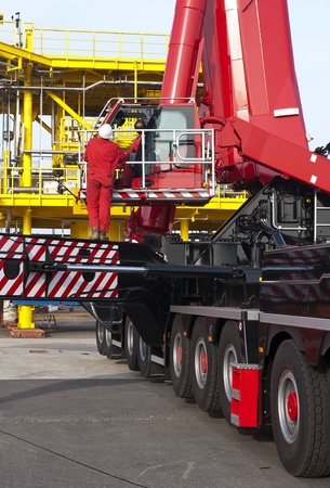 Construction workers, operating a huge mobile crane lifting the drilling platform onto an oil rigの写真素材