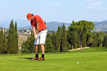 Golfer putting a ball on the green of a golf courseの写真素材