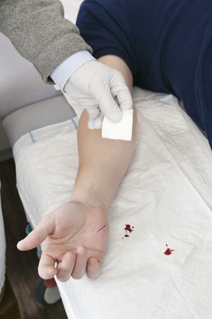 Doctor cleaning the cut on a patient's hand with a piece of gauzeの写真素材