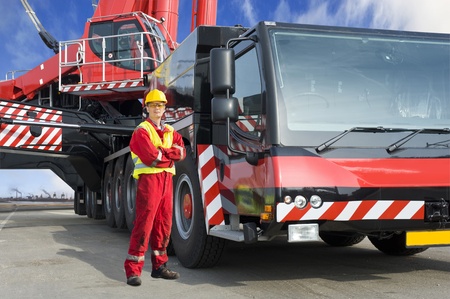 Crane driver, posing next to the huge mobile crane he's operatingの写真素材