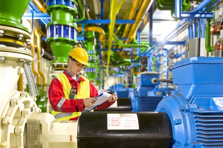 Engineer looking aty a checklist during maintenance work in a large industrial engine room