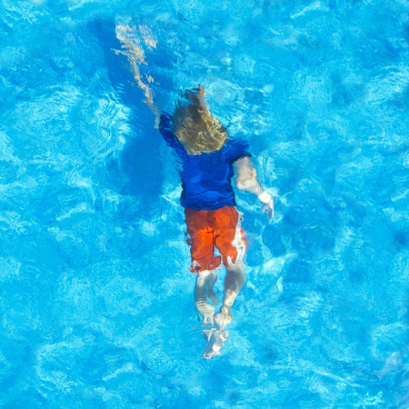 Young child swiming with his clothes on under water, seen from aboveの写真素材