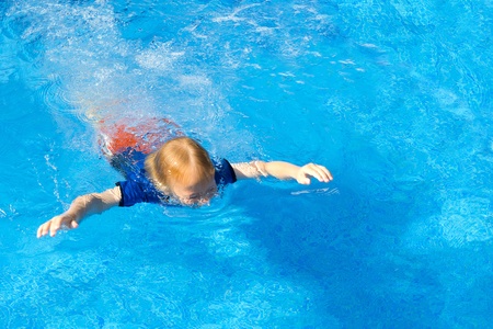 Young boy learning to swim with his clothes on in a poolの写真素材