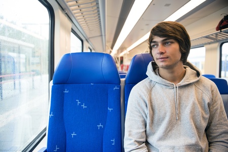 Young Man Travelling In Train, Looking Out Of Window