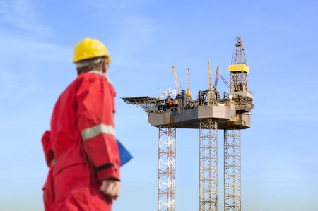 Roughneck (out of focus) looking at a huge oil rig being constructed.の写真素材