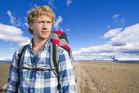 Portrait of a hiker in front of the vast, volcanic tundra landscape of Sprengisandur in Iceland, in...