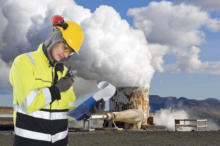Geothermal engineer and geologist reading data from a list at a gothermal power plant in Iceland, creating hot water and sustainable energy from natural resourcesの写真素材