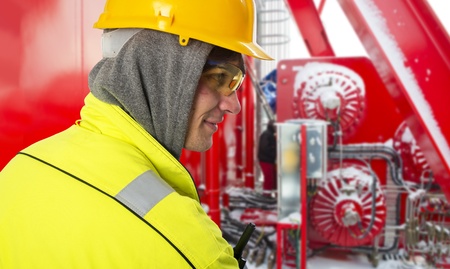 Shipping engineer on a cold winter day, on the snowy bridge of an offshore support vessel, wearing a hoodie and safety gear, such as a hard hat, goggles and reflective coatの写真素材