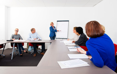 Plenary meeting of a small company, gathered in a meeting room around a flip overの写真素材