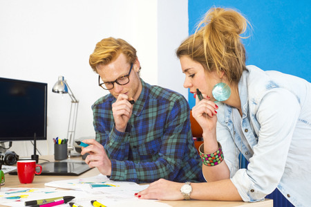 Two colleagues working together on an innovative product design in a creative studio behind a desk,...