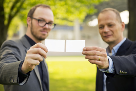 Two smart casually dressed businessmen presenting their business cards to a new networkの写真素材