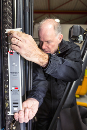 Man measuring the chain of a forkliftの写真素材