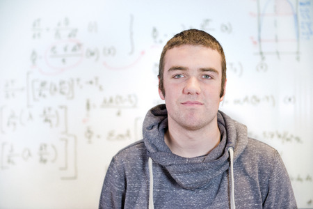 Smart, young, mathematician, posing in front of a whiteboard with complex calculations, formulas and functions.の写真素材