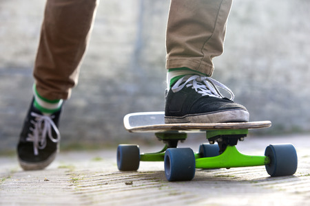 Skateboarder setting his board in motion by pushing off with one foot in an urban setting, representing the youth (sub) cultureの写真素材