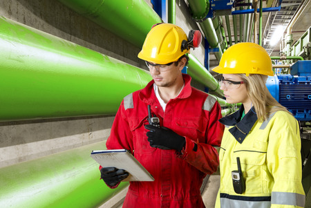 two maintenance engineers going through a checklist during a routine inspection of an industrial installation in a factory two maintenance engineers going through a checklist during a routine inspection of an industrial installation in a factory