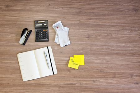 Background of various desktop items on a wooden surface. Items include a stapler, calendar, pen,...
