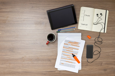 Exam week background, with various study and educted related items, such as a highlighted reader with standard (lorum ipsum) text, a cup of coffee, electronic tablets, music player and ear plugs, and a calendar with the exam date marked Exam week background, with various study and educted related items, such as a highlighted reader with standard (lorum ipsum) text, a cup of coffee, electronic tablets, music player and ear plugs, and a calendar with the exam date marked
