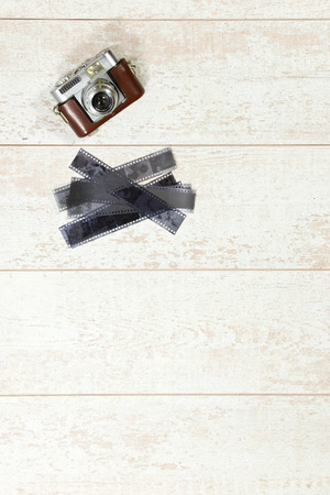 Vintage photography background with a retro rangefinder and 35 negative film strips on a white wooden surfaceの写真素材