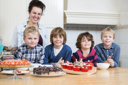 Portrait of happy group of kids, with desserts at kitchen counterの写真素材